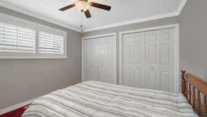 Bedroom featuring multiple closets, ceiling fan, crown molding, and carpet floors