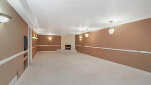 Basement with crown molding, a fireplace, and light colored carpet