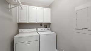 Laundry room with washing machine and clothes dryer, electric panel, and cabinets