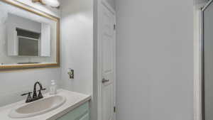 Bathroom featuring vanity, walk in shower, and backsplash