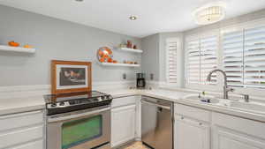 Kitchen featuring white cabinetry, sink, and stainless steel appliances