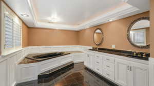 Bathroom featuring vanity, a tub, and a raised ceiling