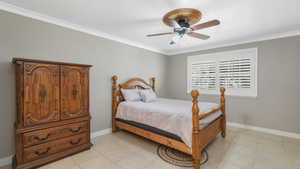 Tiled bedroom with ornamental molding and ceiling fan