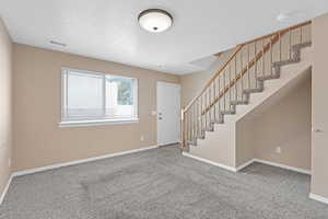 Carpeted entrance foyer featuring a textured ceiling