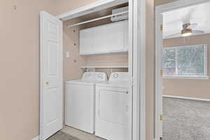 Washroom with cabinets, light carpet, washer and clothes dryer, and ceiling fan