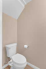 Bathroom with a textured ceiling, toilet, lofted ceiling, and wood-type flooring