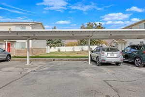 View of parking / parking lot with a carport and a yard