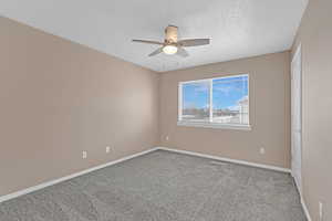 Unfurnished room with a textured ceiling, carpet floors, and ceiling fan