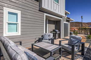 Wooden terrace with area for grilling, central AC unit, and an outdoor hangout area