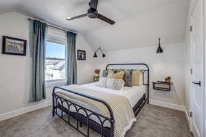 Bedroom with ceiling fan, light carpet, and vaulted ceiling