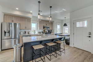 Kitchen with light brown cabinets, a center island, stainless steel appliances, and light hardwood / wood-style floors