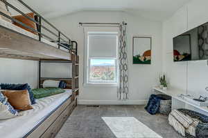 Carpeted bedroom featuring vaulted ceiling