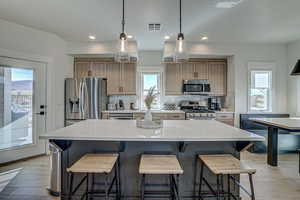 Kitchen with a center island, backsplash, stainless steel appliances, and light hardwood / wood-style floors