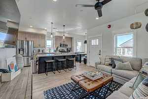 Living room with a wealth of natural light, sink, ceiling fan, and light wood-type flooring