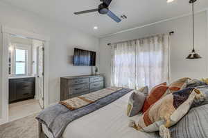 Tiled bedroom featuring ensuite bath and ceiling fan