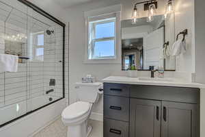 Full bathroom featuring shower / bath combination with glass door, tile patterned floors, vanity, and toilet