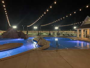 Pool at night featuring a patio area