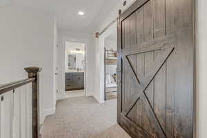 Hall featuring a barn door, light colored carpet, and sink