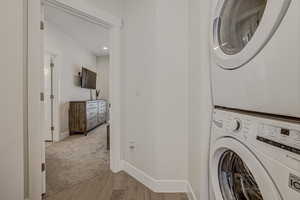 Laundry area featuring light hardwood / wood-style flooring and stacked washer and clothes dryer