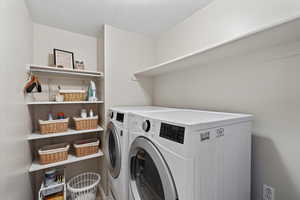 Laundry area featuring washing machine and clothes dryer and a textured ceiling