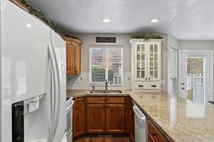 Kitchen with sink, dark hardwood / wood-style flooring, tasteful backsplash, white appliances, and a textured ceiling