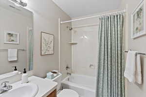 Full bathroom with vanity, shower / tub combo, a textured ceiling, and toilet