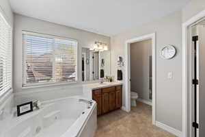 Bathroom with vanity, a tub to relax in, and toilet