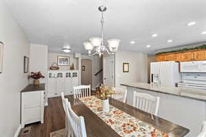 Dining space with a chandelier and dark wood-type flooring