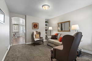 Living room with carpet flooring and a textured ceiling