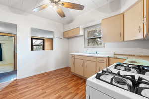 Kitchen featuring white gas range oven, light hardwood / wood-style floors, ceiling fan, and sink