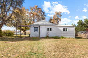 View of outdoor structure featuring a lawn