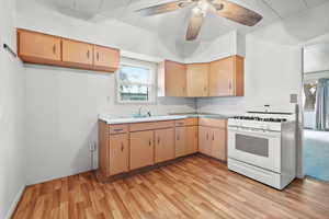 Kitchen featuring ceiling fan, light hardwood / wood-style floors, sink, and white range with gas cooktop