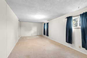 Empty room featuring light colored carpet and a textured ceiling