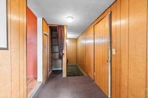 Hallway with wood walls, hardwood / wood-style floors, and a textured ceiling