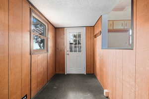 Entryway with a textured ceiling and wooden walls