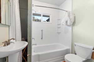 Full bathroom with shower / bath combination with curtain, toilet, and sink