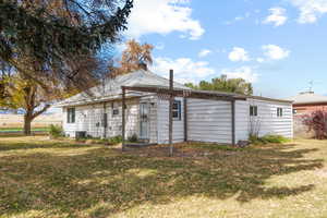 Rear view of house featuring a lawn and central air condition unit