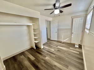 Unfurnished bedroom with ceiling fan, hardwood / wood-style floors, a textured ceiling, and wooden walls