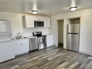 Kitchen with white cabinets, dark hardwood / wood-style floors, and appliances with stainless steel finishes