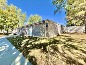 View of side of home with central AC unit and a lawn