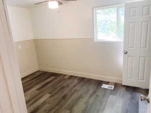 Empty room featuring dark hardwood / wood-style flooring and ceiling fan