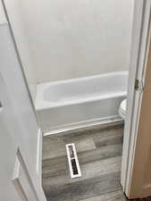 Bathroom featuring hardwood / wood-style floors, a bath, and toilet