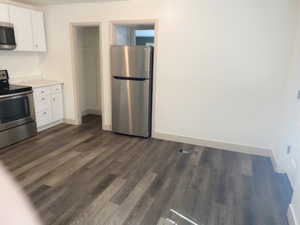 Kitchen with dark hardwood / wood-style floors, white cabinetry, and appliances with stainless steel finishes