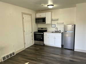 Kitchen featuring dark hardwood / wood-style floors, sink, white cabinetry, and stainless steel appliances