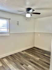 Unfurnished room featuring a textured ceiling, ceiling fan, and dark wood-type flooring