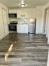 Kitchen featuring appliances with stainless steel finishes, dark hardwood / wood-style floors, white cabinetry, and sink