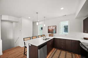 Kitchen featuring stainless steel dishwasher, a kitchen breakfast bar, kitchen peninsula, and hardwood / wood-style flooring