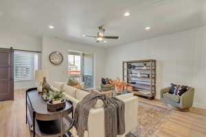 Living room with a barn door, plenty of natural light, and light hardwood / wood-style flooring