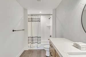 Full bathroom featuring tile patterned floors, shower / bath combo with shower curtain, vanity, and toilet