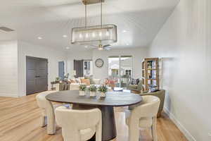 Dining room featuring a barn door, ceiling fan with notable chandelier, and light wood-type flooring